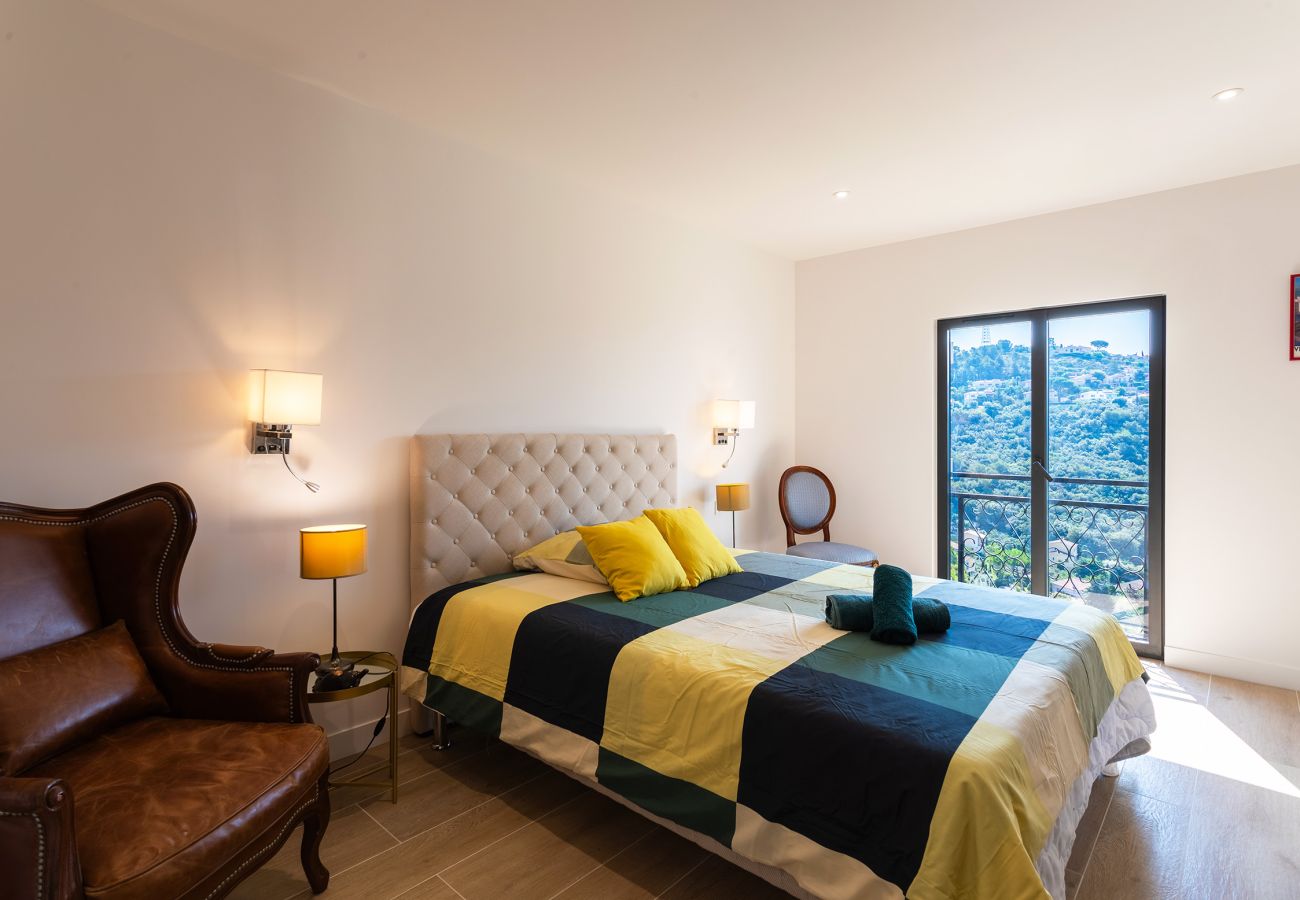 Modernes Schlafzimmer mit geräumigem Bett, elegantem Sessel und Balkon mit herrlicher Aussicht auf die Natur.