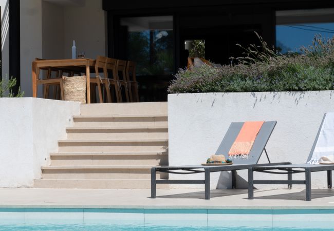 Villa Le 41 - Photo zoomée de la piscine, des chaises longues, et la terrasse couverte avec table à manger et vin 