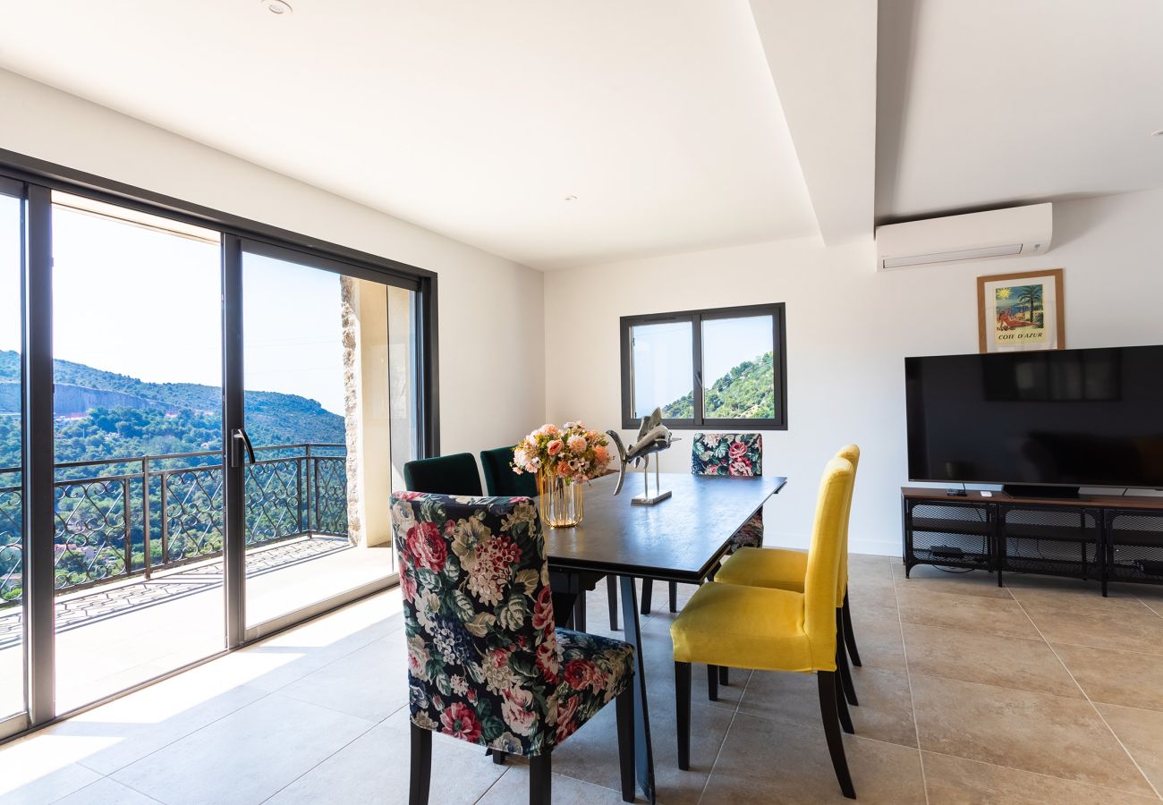 Salle à manger lumineuse avec vue imprenable sur les collines, décorée avec élégance et conçue pour des repas confortables.